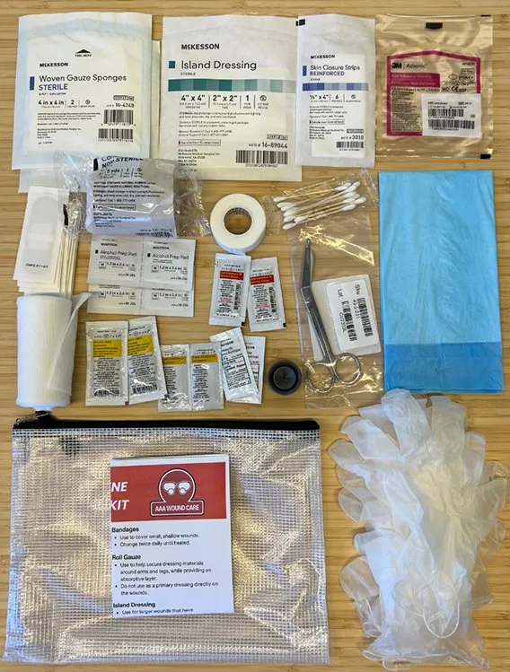 Contents of an advanced wound care kit laid out: dressings, gauze, ointment packets, gloves, and irrigation cap