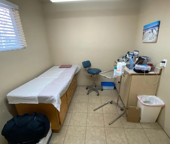 medical examination room with exam table, chair, cabinets, and medical supplies