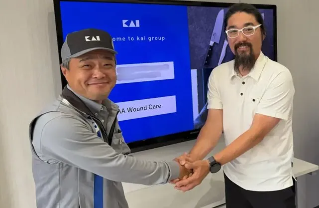 Dr. Aram shaking hands with a KAI Medical representative in front of a “Welcome to KAI group” screen