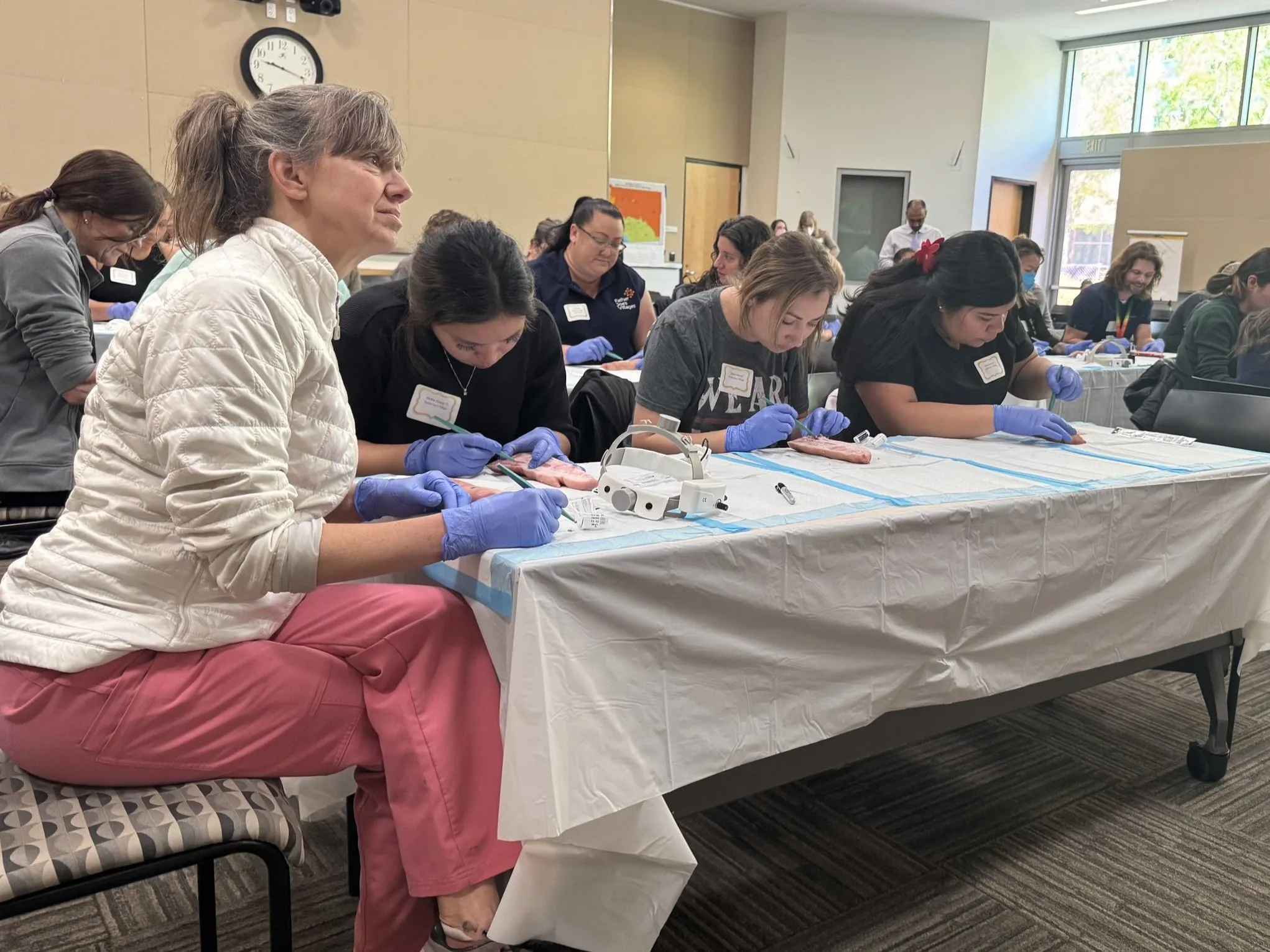 People participating in a medical training workshop, working on practice materials at tables.