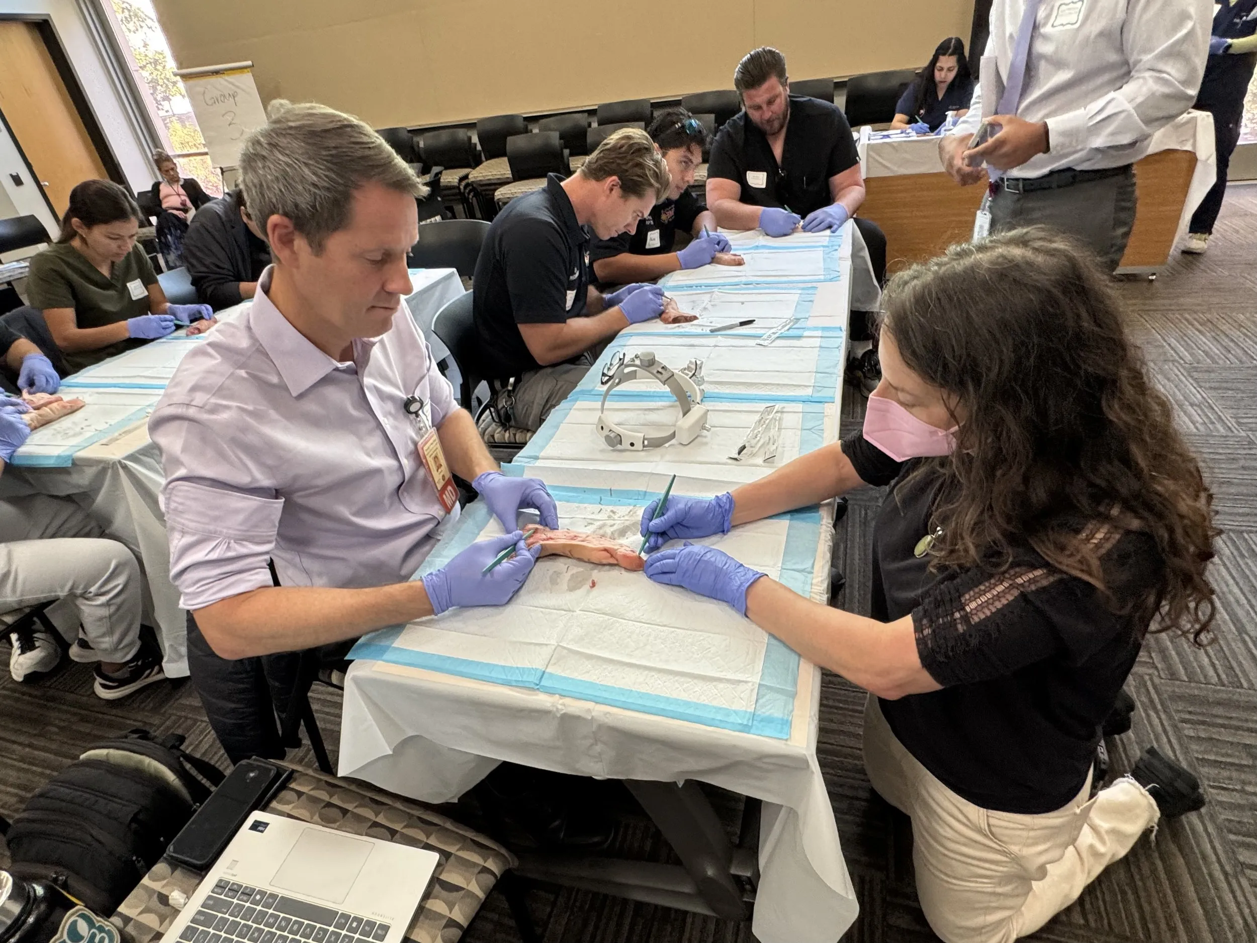 People in a classroom setting practicing surgical skills on animal specimens.