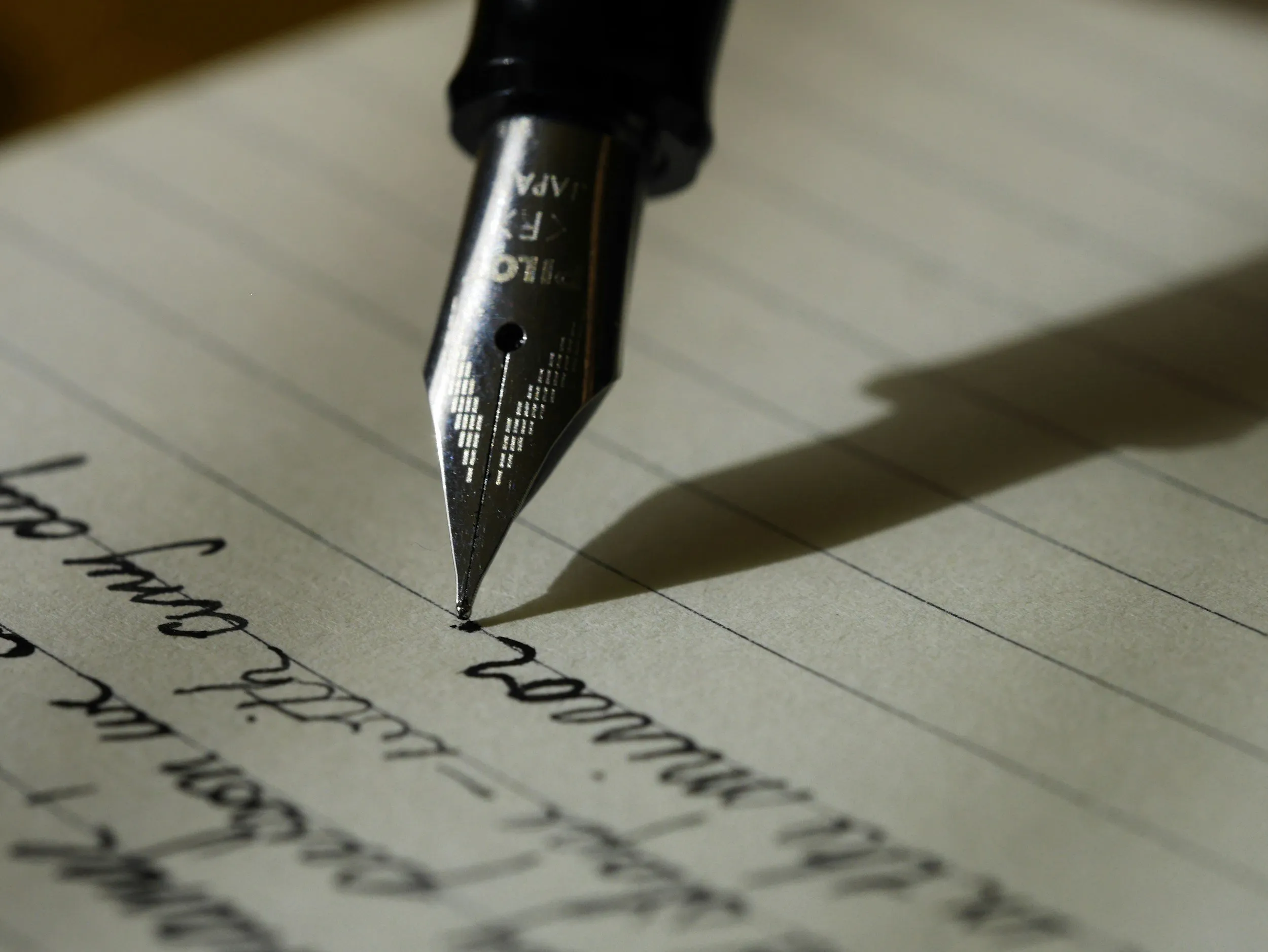 Close-up of a fountain pen writing on lined paper.