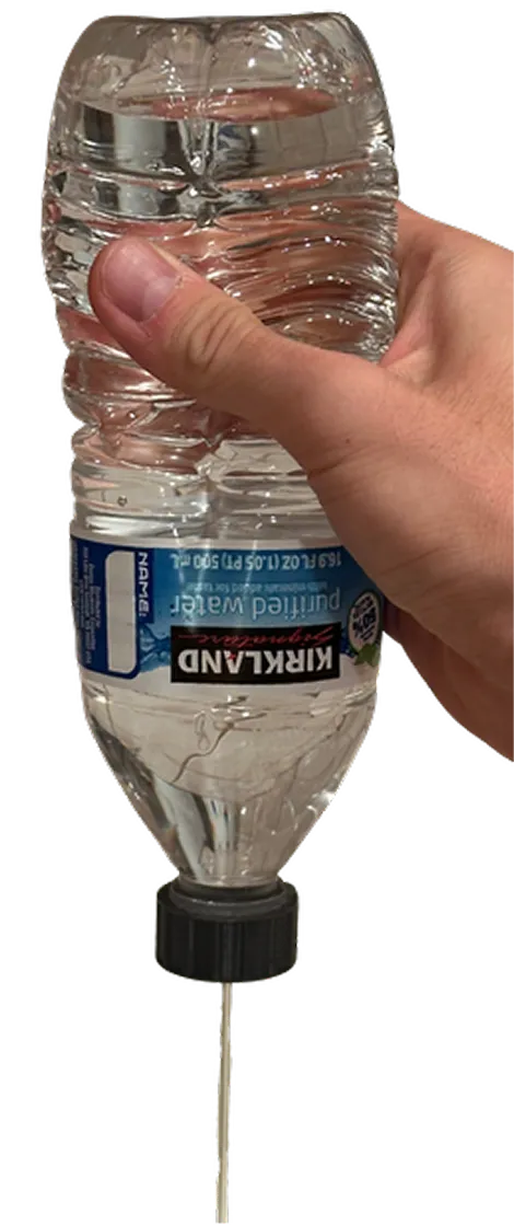 Hand squeezing a water bottle fitted with the irrigation cap to produce a controlled stream of water
