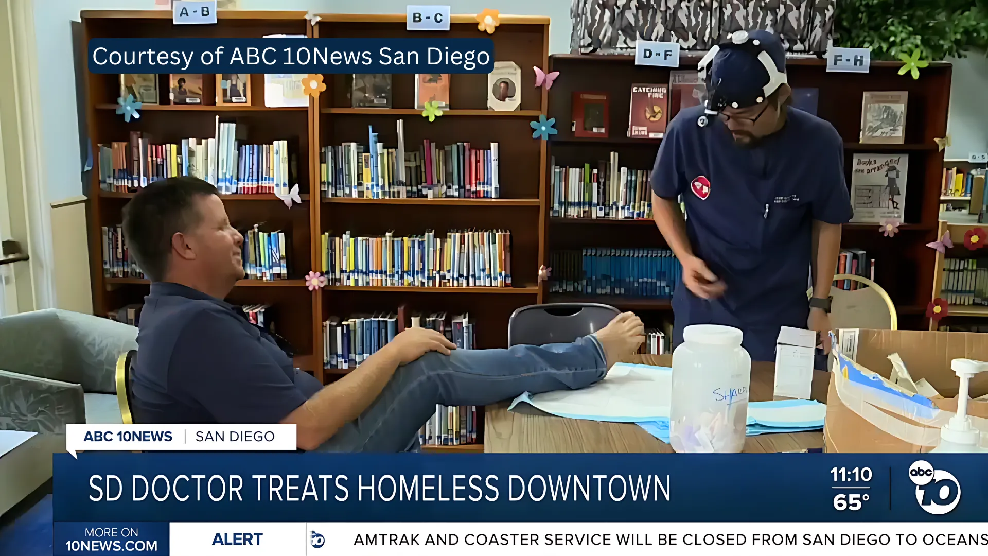 A doctor in scrubs is treating a patient in a library setting. The overlay text reads, "SD Doctor Treats Homeless Downtown," along with a courtesy label from ABC 10News San Diego.