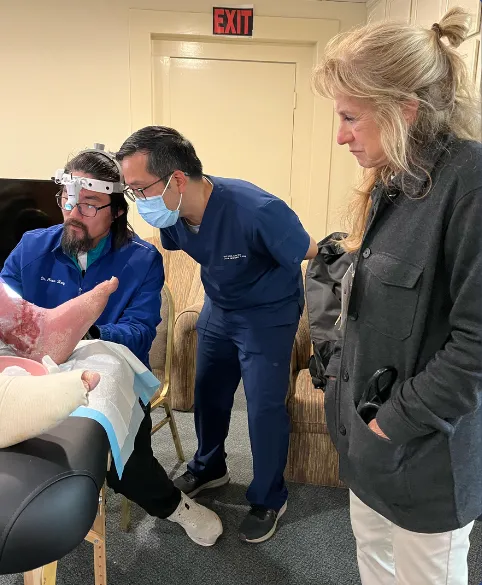 A group of medical professionals examining a patient's foot in a clinical setting.