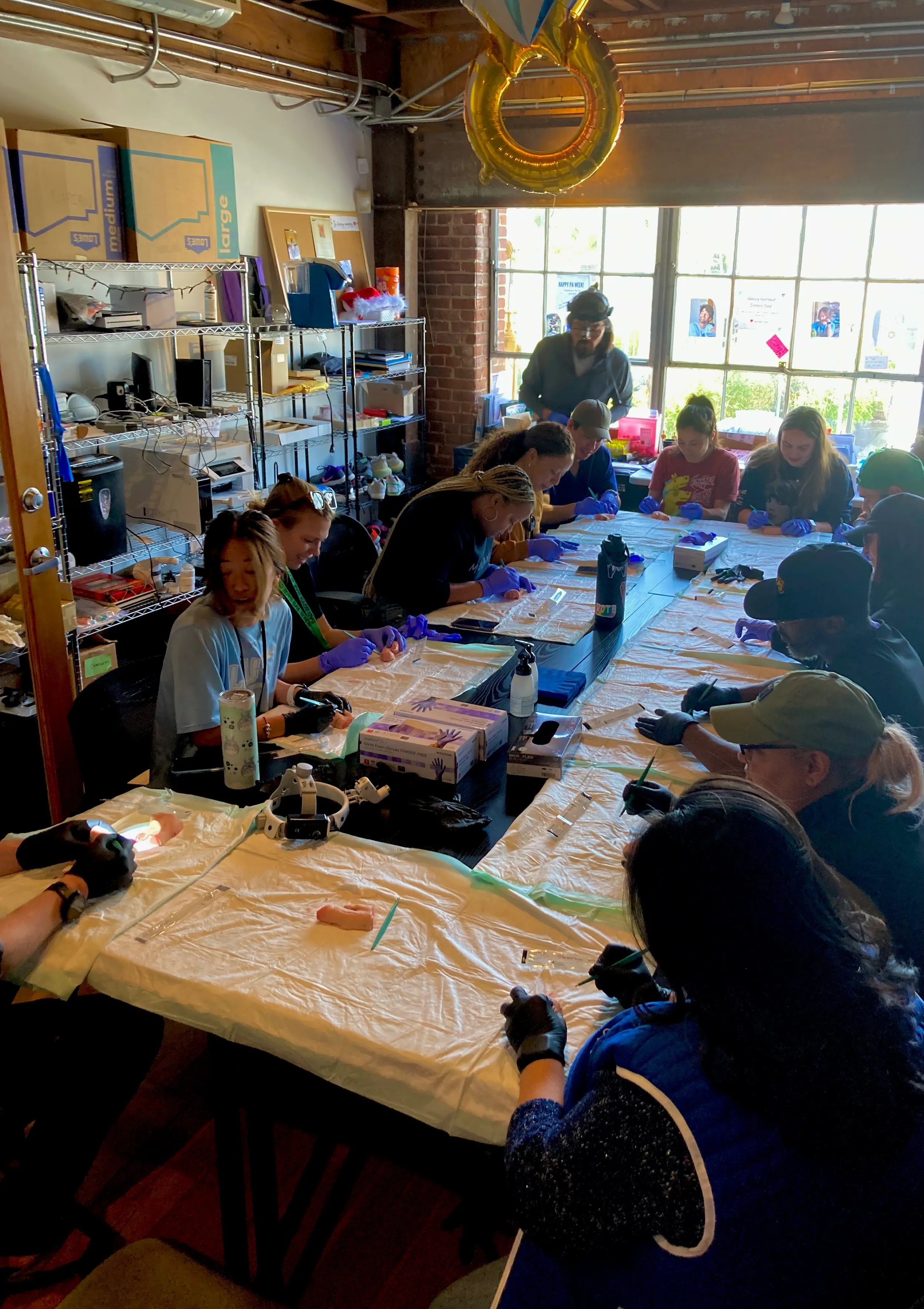A group of people sitting around a table engaging in a workshop or hands-on activity, wearing gloves.