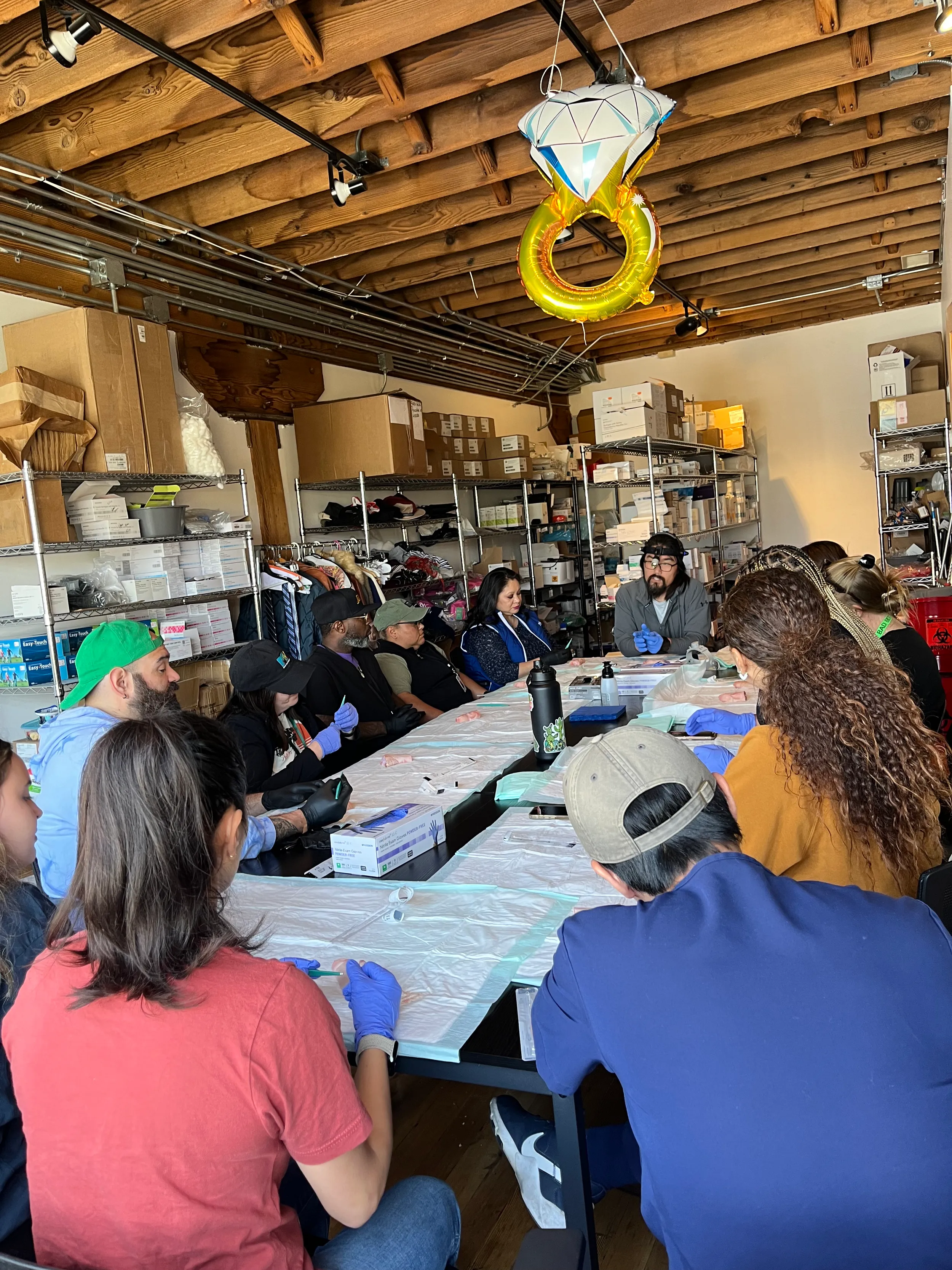 A group of people wearing gloves sitting around a table covered with protective sheets.